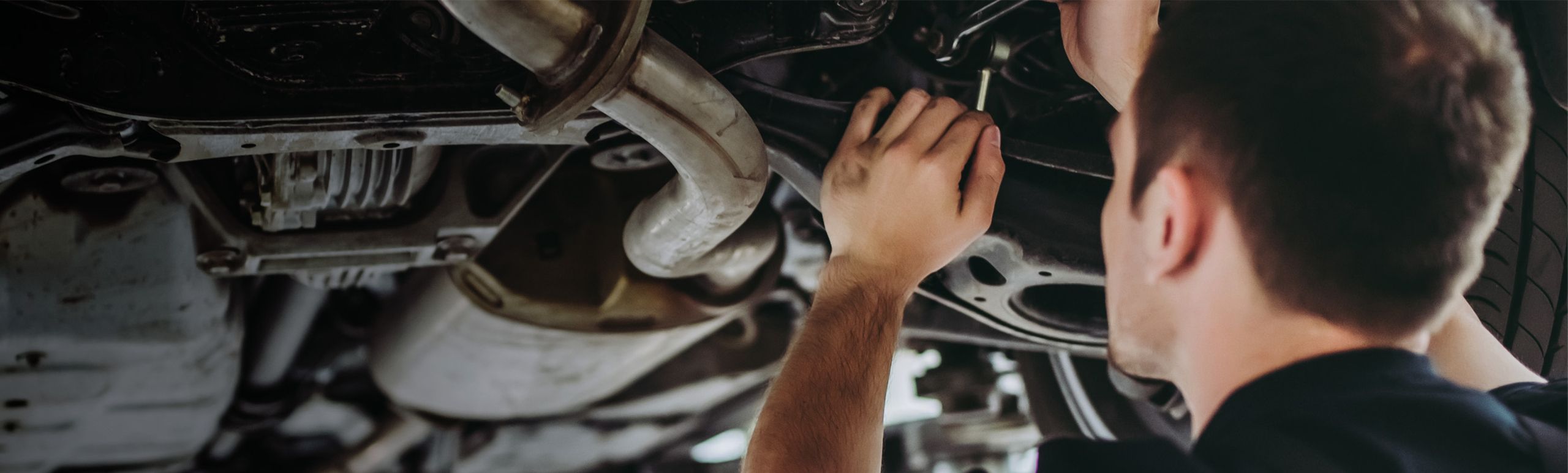 Ein KFZ-Mechaniker der unter einem Auto Arbeiten verrichtet